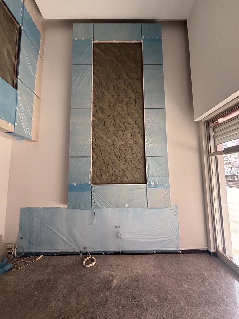 Çayırlı İş Merkezi lobi uygulamasında koruyucu filmli açık paneller ve koyu dokulu merkez yüzey