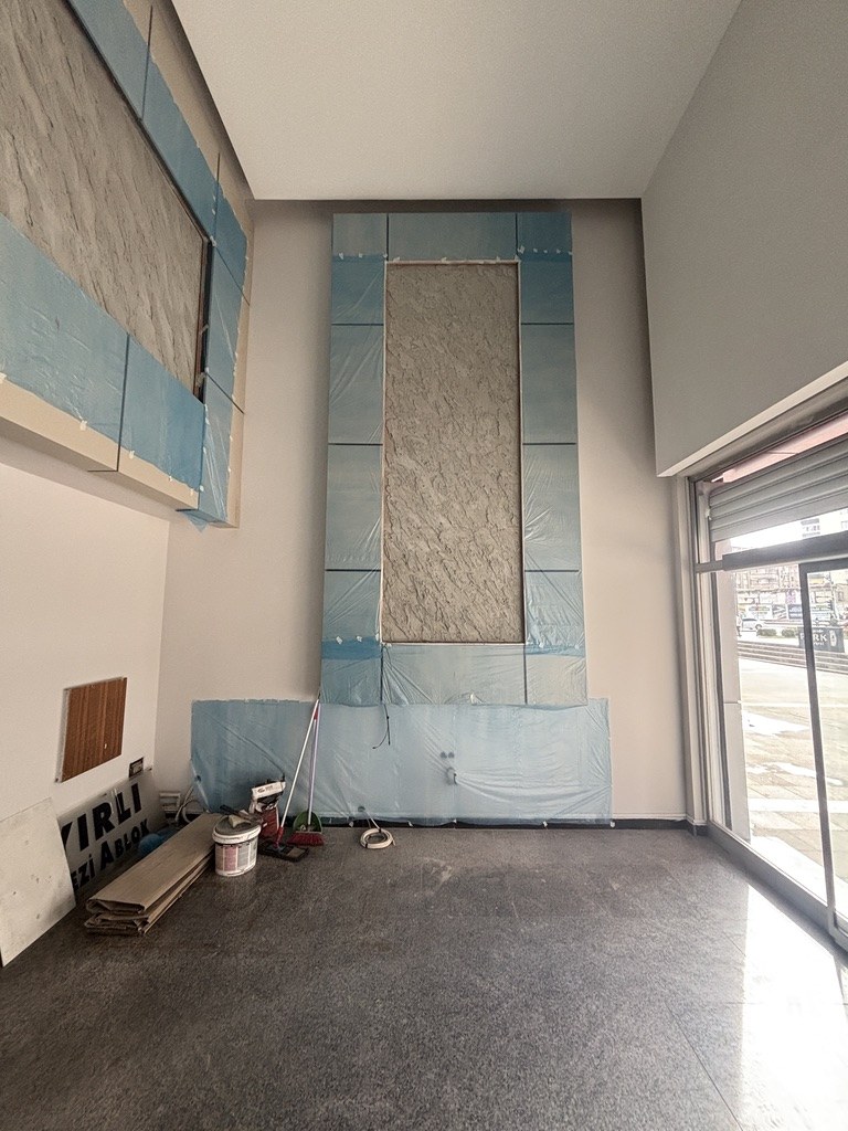 Çayırlı İş Merkezi lobi duvarında koruyucu filmleri üzerinde bırakılmış modüler paneller ve tamamlanan dokulu yüzey